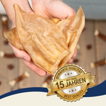 Eine Person hält einen großen, zähen Hundekeks in den Händen, mit einem goldenen Abzeichen, das 'Beste Qualität' und '15 Jahre' auf Deutsch angibt.