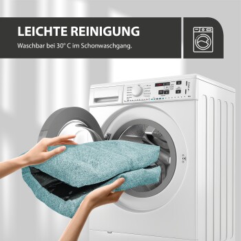 Eine Person legt ein türkisfarbenes Haustierbett in eine Waschmaschine, mit dem Text "LEICHTE REINIGUNG" und "Waschbar bei 30° C im Schonwaschgang" darüber.