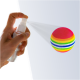 Eine Hand hält eine Sprühflasche, die einen bunten, gestreiften Haustier-Spielzeugball besprüht, der lebendige Farben in Pink, Gelb, Grün und Blau zeigt.