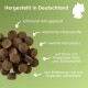 Haustierfutterpellets auf grünem Hintergrund mit Text: "Hergestellt in Deutschland", "kaltgepresst", "natürlich", "weiche Textur", "Insektenprotein & Süßkartoffel."