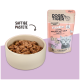 Eine beige Schüssel mit feuchtem Katzenfutter neben einem rosa Beutel mit der Aufschrift "DOGS'n'TIGER KLIMBIM" mit einem Katzenkopf und "Leckeres Geflügel mit Kalb & Karotte."