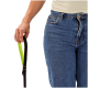 Nahaufnahme einer Person in Jeans, die eine schwarz-neongrüne Hundeleine in der Hand hält.