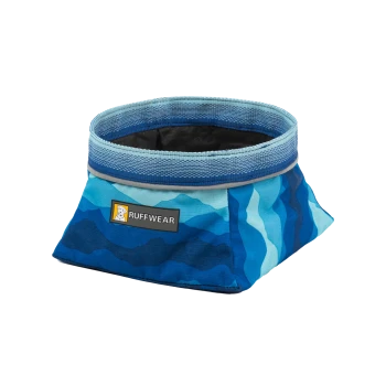 Eine blaue und türkisfarbene zusammenklappbare Haustierschüssel von Ruffwear, mit einem strukturierten Rand und einem Logo-Patch an der Seite.