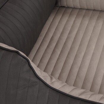 Eine Nahaufnahme eines Haustierbettes mit einem dunkelgrauen, gerippten äußeren Rand und einem weichen, hellbeigen gestreiften Inneren.