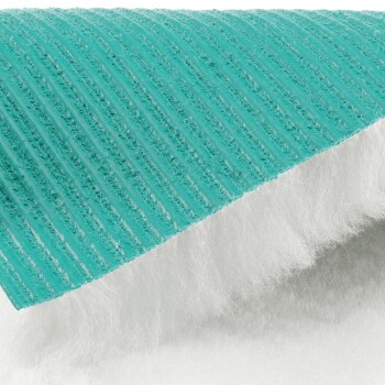 Nahaufnahme einer türkis-weißen, strukturierten Haustier-Trainingsmatte mit sichtbaren saugfähigen Schichten.