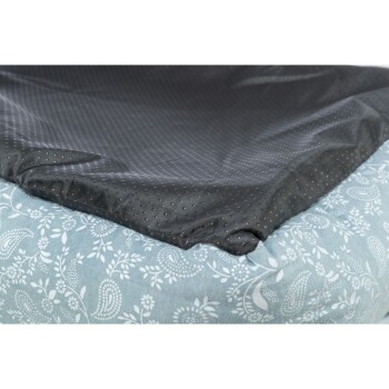 Nahaufnahme eines Haustierbettes mit einem weichen, blumengemusterten blauen Stoff an den Seiten und einer glatten, dunkelgrauen Oberseite mit kleinen Punkten.