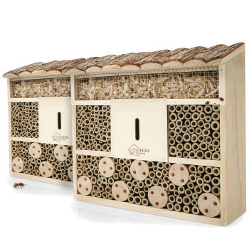 Holz-Insektenhotel mit der Aufschrift 'wildlife home', Bambusröhren, gebohrten Holzscheiben, Rindendach und gitterförmiger Oberseite, gefüllt mit Holzspänen
