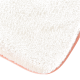 Eine Nahaufnahme einer weichen, flauschigen Haustiermatte in Cremefarbe mit einem rosa Rand, die ihre plüschige Textur und abgerundeten Kanten zeigt.