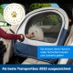 Ein kleiner weißer Hund in einer Transportbox im Auto, mit einer Person, die ihn streichelt. Enthält ein Abzeichen "2022 PET INNOVATION AWARD."