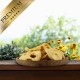 Holzteller mit getrockneten Apfelscheiben auf einer Holzoberfläche, umgeben von grünen Pflanzen und gelben Blumen, mit der Aufschrift Premium.