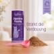 Graue Katze frisst aus einer Metallschale neben einer violetten KatKare-'Digestive Topping'-Dose und einer rosa Schaufel mit verschüttetem Pulver.