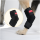 Hund trägt eine schwarze Beinorthese mit rotem Etikett am Hinterbein, isoliert auf weißem Hintergrund.