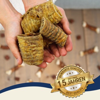 Eine Person hält mehrere gerollte Hundeleckerlis in ihren Händen, mit einem Abzeichen, das "Beste Qualität" und "15 Jahre" auf Deutsch angibt.