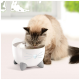 Un chat duveteux boit d'une fontaine à eau en forme de chat blanche avec des pattes grises, sur fond lumineux et doux.