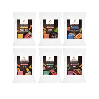 Sechs Wildfang-Marken-Tiernahrungspakete mit Angus-Rindfleisch, Lamm, Lachs mit Forelle, Ente, Thunfisch und Wildfleisch mit Bildern der jeweiligen Zutaten.