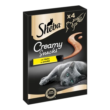 Emballage de friandises pour chats Sheba Creamy Snacks avec un chat gris allongé sur une surface noire, avec un tube de friandise crémeuse étiqueté 'mit Huhn au poulet.'