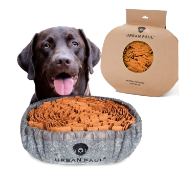 Ein gemütliches Hundebett gefüllt mit orangefarbenen Kauknochen, gekennzeichnet mit "URBAN PAUL®", neben einer runden Verpackung, die "NATÜRLICHE INSTINKTE TREFFEN" liest.