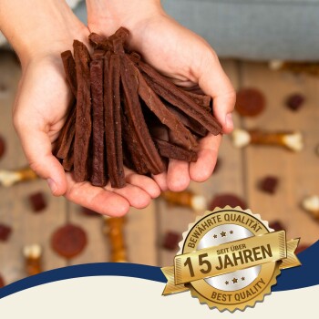Eine Person hält eine Handvoll dunkelbrauner Haustierleckerlis, mit einem Badge-Overlay, das "Beste Qualität" und "Bewährte Qualität seit über 15 Jahren" angibt.