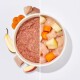 Schüssel mit Haustierfutter mit Etiketten für die Zutaten: Muskelfleisch, Apfel, Birne, Leinsamenöl, Innereien und Karotten.