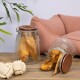 Zwei Glasbehälter gefüllt mit Hundeleckerlis, einer aufrecht und einer umgekippt, neben einem plüschigen Haustierbett und einem Seilspielzeug auf einer Holzoberfläche.
