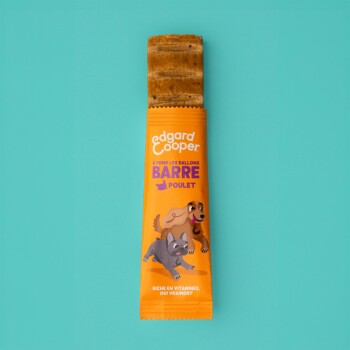 Barre de friandise pour chien Edgard Cooper dans un emballage orange présentant des chiens de dessin animé, étiquetée "BARRE POULET" et "RICHE EN VITAMINES, OUI VRAIMENT."
