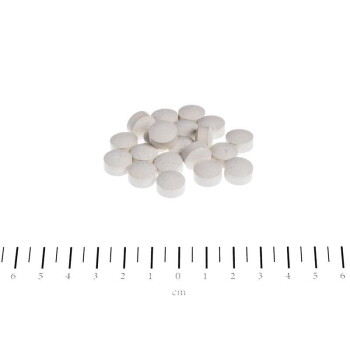 Haufen kleiner weißer runder Tabletten auf weißem Hintergrund über einem Zentimeterlineal mit Zahlen und 'cm'.