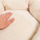 Eine Hand drückt sanft auf ein weiches, cremefarbenes Haustierbett mit einer strukturierten Oberfläche, das seinen plüschigen Komfort zeigt.