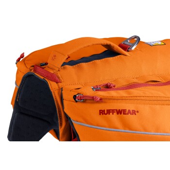 Nahaufnahme eines orangefarbenen Hunderrucksacks von Ruffwear, der Reißverschlüsse, einen Griff und reflektierende Akzente aufweist.