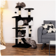 Ein mehrstöckiger Katzenbaum in Schwarz und Grau mit vier flauschigen Katzen, die sich entspannen und spielen, in einem gemütlichen Wohnzimmer mit einem grauen Sofa.