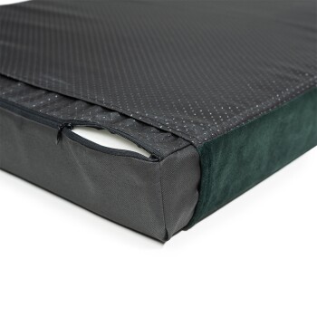 Eine Nahaufnahme eines Haustierbettes mit einem Reißverschlussbezug, der eine strukturierte schwarze Oberseite und eine weiche grüne Seite zeigt, um sein Design und Material zu präsentieren.