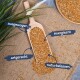 Eine Holzschaufel mit Samen auf Jute, umgeben von grünen Blättern, mit Etiketten: "ausgewogen", "energiegebend", "artengerecht", "natürlich."