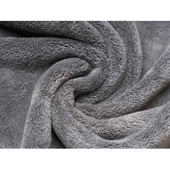Weiche, graue Tierdecke mit einer plüschigen Textur, in einem spiralförmigen Muster angeordnet.