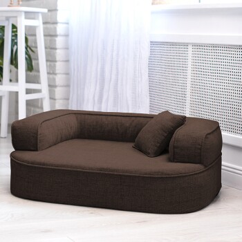 Braunes Haustierbett mit gepolstertem Design und einem kleinen Kissen, auf einem hellen Holzboden mit weißem Hintergrund platziert.