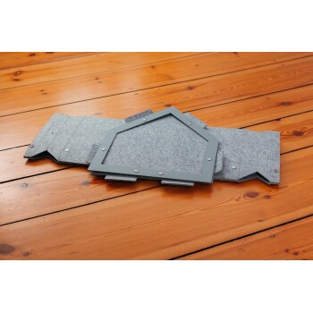 Ein faltbares Haustierhaus aus grauem Filz, mit einem sechseckigen Rahmen und Metallverschlüssen, auf einem Holzboden platziert.