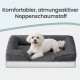 Kleiner weißer Hund auf grauem Haustierbett mit Rand; Text oben: 'Komfortabler, atmungsaktiver Noppenschaumstoff'