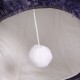 Ein gemütliches Haustierbett-Interieur mit einem weichen weißen Pom-Pom-Spielzeug, das an einem Faden hängt, umgeben von plüschigem Stoff.