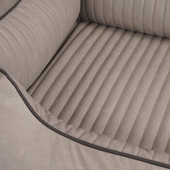 Eine Nahaufnahme eines plüschigen, beigen Haustierbettes mit geripptem Design und einem kontrastierenden dunklen Rand.