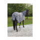 Ein Pferd, das eine schwarz-weiße Decke mit Zebra-Muster trägt, steht auf Kies, umgeben von grünen Bäumen.