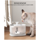 Eine hellfarbige Katze trinkt aus einem modernen Haustier-Wasserbrunnen auf einem Holzboden. Der Text darüber sagt "Höchste Sicherheit" und "Schützt Tiere."