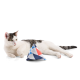 Eine weiße Katze mit schwarzen Flecken liegt neben einem bunten dreieckigen Spielzeug mit blauen, roten und weißen Mustern auf einem weißen Hintergrund.