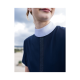 Nahaufnahme einer Person, die ein marineblaues Kleid mit einem weißen Kragen und einem glitzernden vertikalen Streifen auf der Vorderseite trägt.