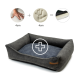 Ein plüschiges, graues Haustierbett mit einem dunkelblauen Kissen, mit einem Pluszeichen-Grafik und Symbolen, die eine Hand und einen Handabdruck darstellen, jeweils beschriftet mit "4cm."
