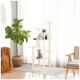 Ein hoher beiger Katzenbaum mit einer flauschigen weißen Katze oben und einer grauen Katze unten, umgeben von Zimmerpflanzen und natürlichem Licht.