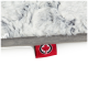 Eine Nahaufnahme einer weichen, grauen Haustierdecke mit flauschiger Textur, mit einem roten Etikett mit einem schwarzen Kreis und einem Ahornblatt-Logo.