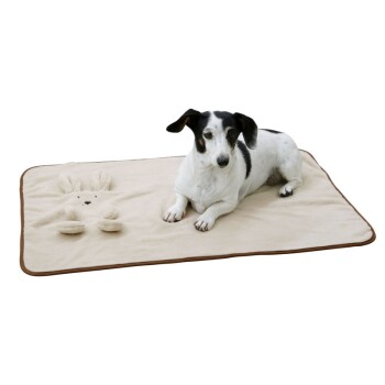 Een zwart-witte hond ligt op een zachte beige huisdiermat met een konijnontwerp, wat comfort en stijl voor huisdieren laat zien.
