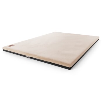 Ein plüschiges, beiges Hundebett mit einem schwarzen Boden, das eine weiche Oberfläche für Komfort bietet.