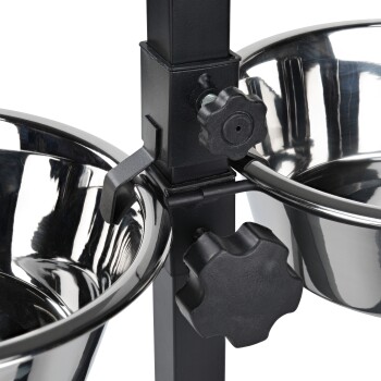 Gros plan d'une station de nourriture pour animaux de compagnie avec deux bols en acier inoxydable montés sur un support noir ajustable avec des boutons pour le réglage de la hauteur.