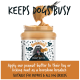 Ein Glas Bugalugs 100% natürliche Erdnussbutter für Hunde, mit einem Löffel, der darüber gehalten wird. Der Text lautet "HÄLT HUNDE BESCHÄFTIGT" und Anweisungen zur Verwendung.