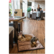 Zwei kleine Hunde ruhen sich auf einer braunen Haustiermatte in einem Restaurant aus, mit Weingläsern und einem reservierten Schild auf dem Tisch in der Nähe.