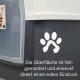 Nahaufnahme eines dunkel strukturierten Panels einer Transportbox mit weißem Pfotenlogo und deutschem Text: 'Die Oberfläche ist fein gemustert...'.
